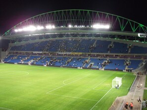 Un estadio grande con múltiples niveles de asientos, un campo bien iluminado y un arco.