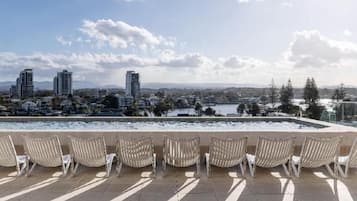 Terraço no telhado com espreguiçadeiras e vista para a cidade.