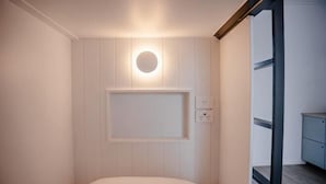 Una habitación con una cama, una lámpara en la pared y un enchufe.