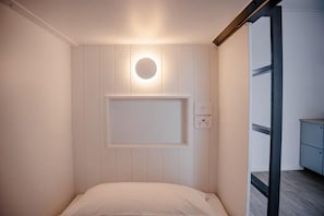 A room with a bed, a wall-mounted light, and a power outlet. - Bounce Surfers Paradise (Gold Coast)