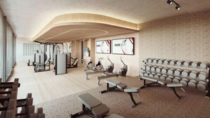 Un gimnasio con equipo de ejercicio, una pared decorada con cuadros enmarcados y suelo de madera.