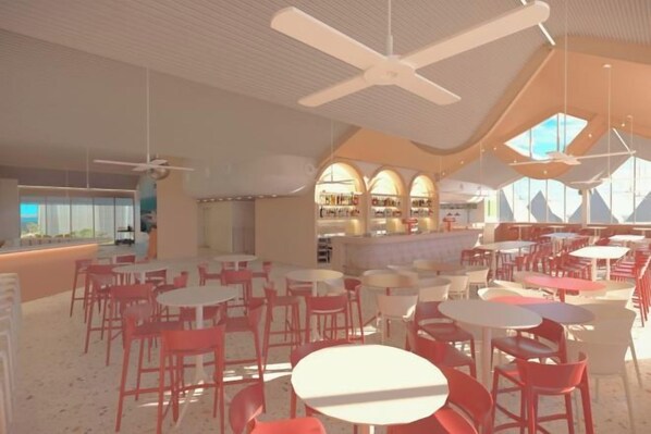 Un espace intérieur vaste et lumineux, avec de nombreuses tables et chaises, un coin bar et une vue dégagée grâce à de grandes fenêtres.