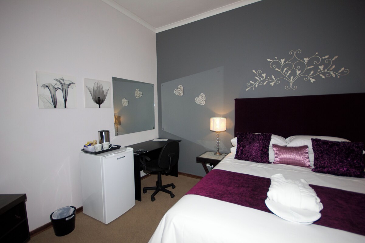 Une chambre d’hôtel équipée d’un lit, d’un bureau, d’une chaise et d’une poubelle.