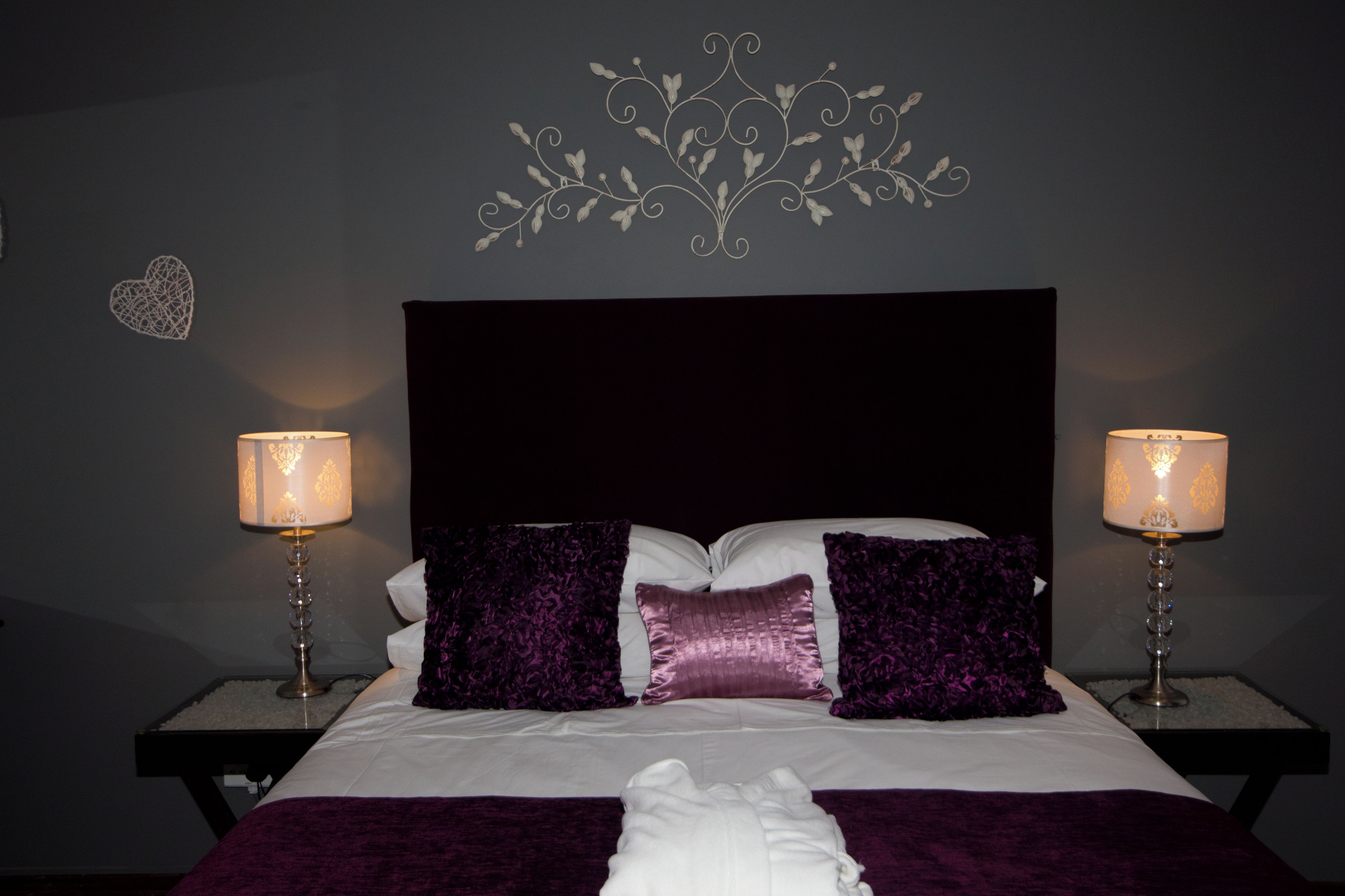 A bed with a headboard, two bedside tables with lamps, and decorative wall art.