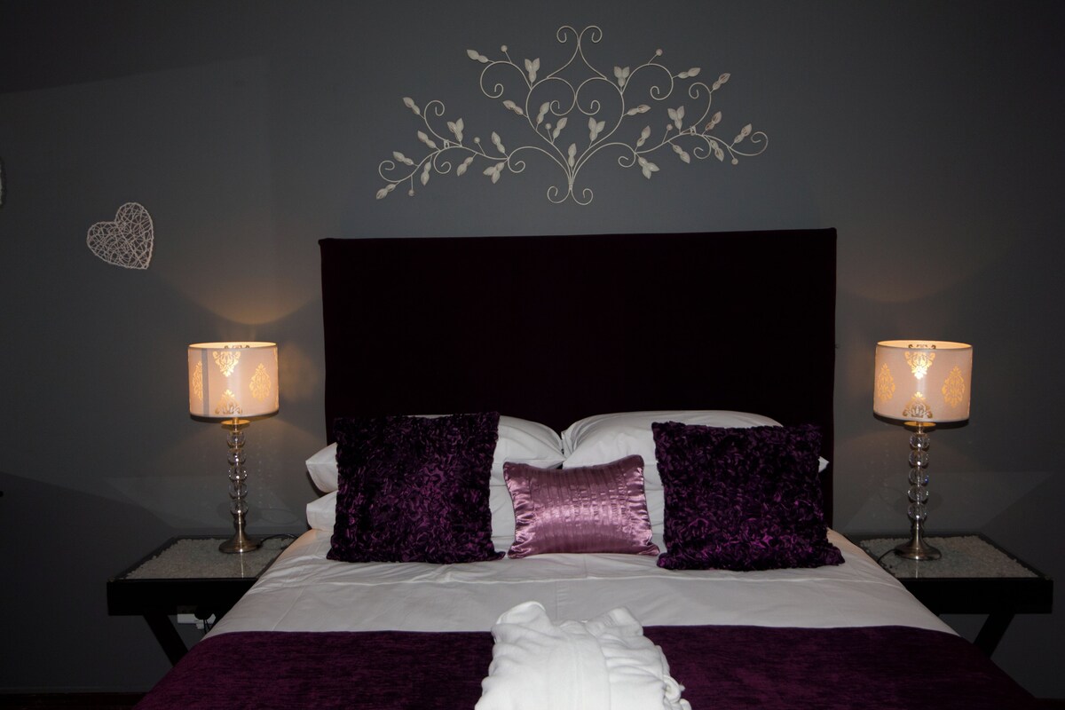 A bed with a headboard, two bedside tables with lamps, and decorative wall art.