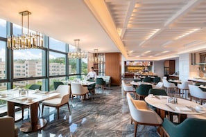 Zona pranzo moderna con ampie finestre, un bar e vista sugli edifici.