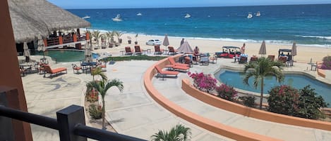 A resort with a pool, lounge chairs, and a beach view.