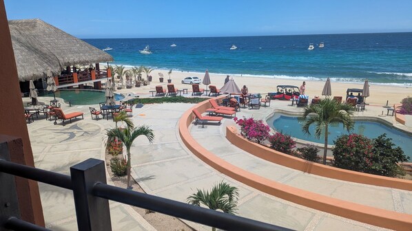 A resort with a pool, lounge chairs, and a beach view.