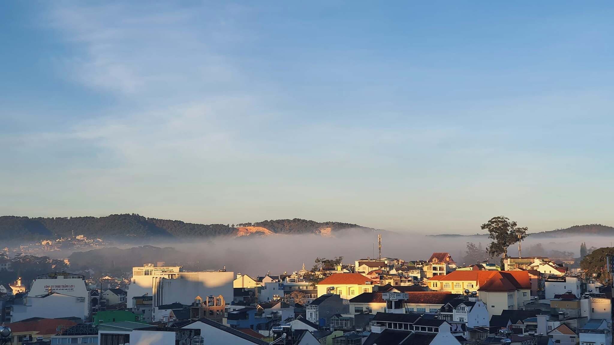 A coastal town with buildings, a church, and a hill in the background.