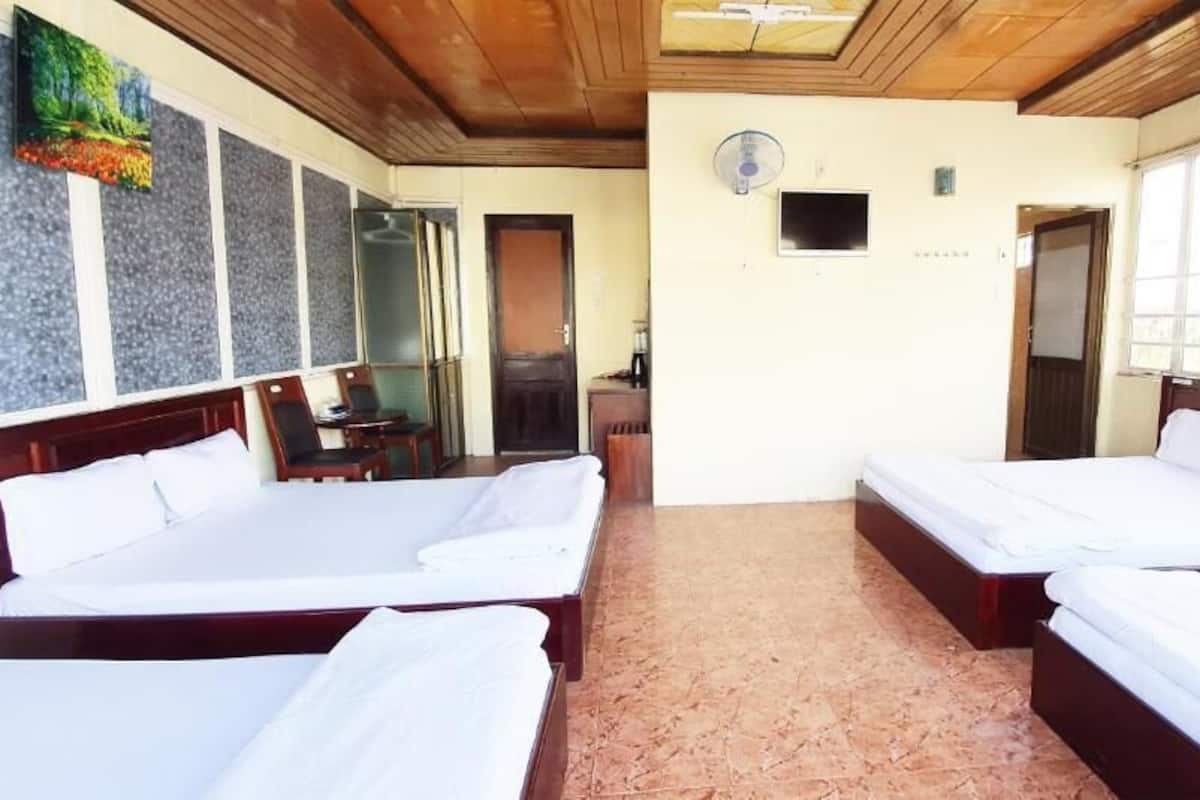 A hotel room with two beds, a TV, a fan, and a window with curtains.