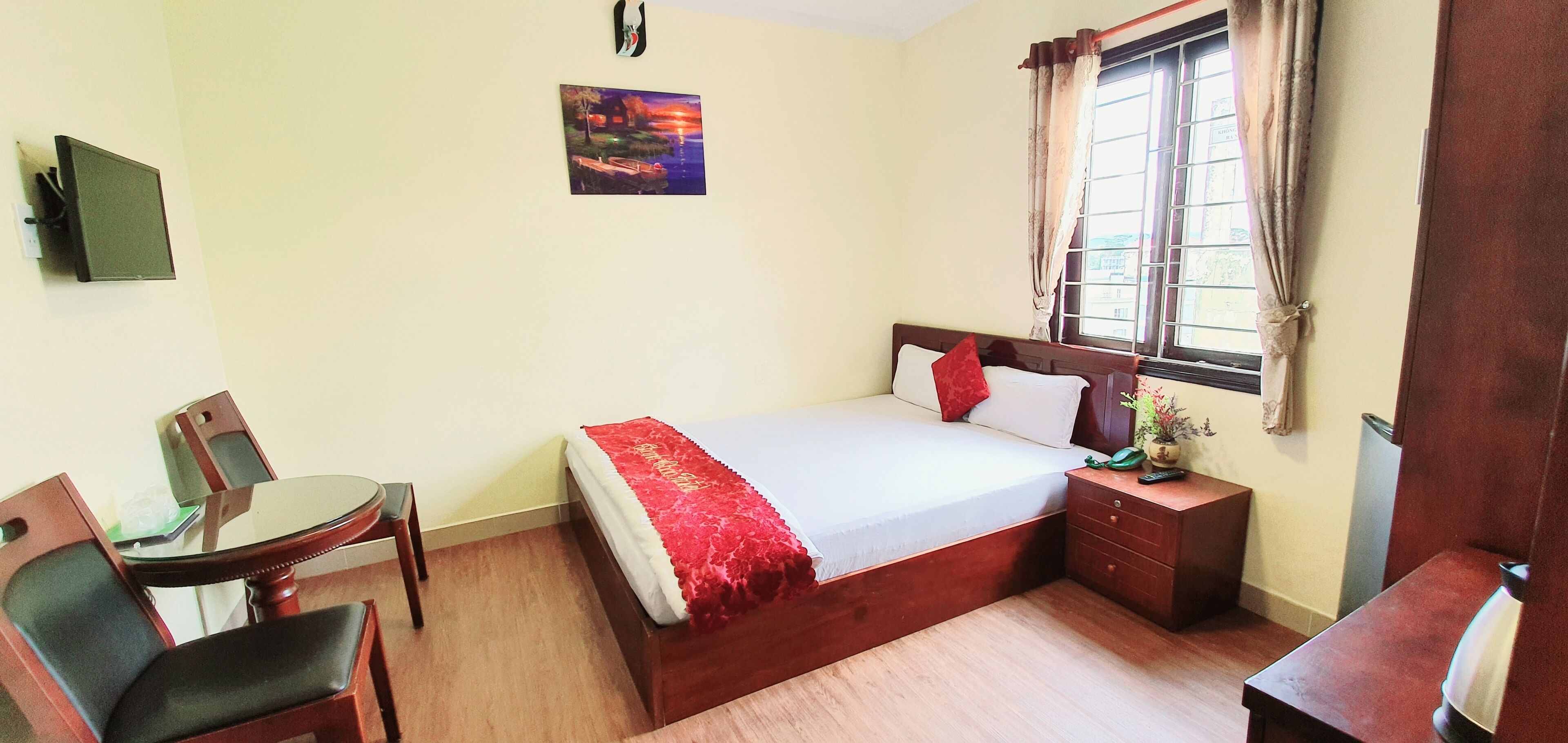 A bedroom with a bed, bedside table, chair, and a window.