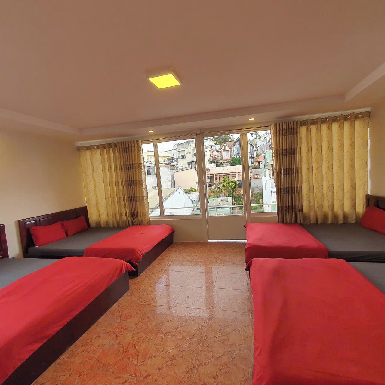 A hotel room with two beds, a large window with curtains, and a view of buildings outside.