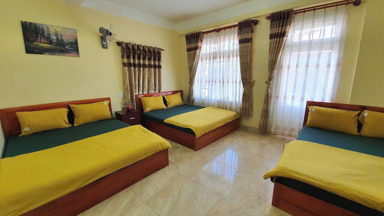 Habitación de hotel con tres camas, un cuadro en la pared y un ventilador de techo.