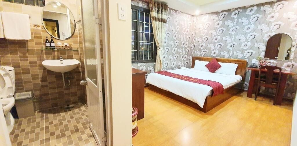 A hotel room with a bathroom, a bed, a desk, and a mirror.