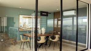 A modern dining area with a glass partition, a wooden table, and chairs. - Paravian 107A 1BR Condo Playa del Carmen (Playa del Carmen)