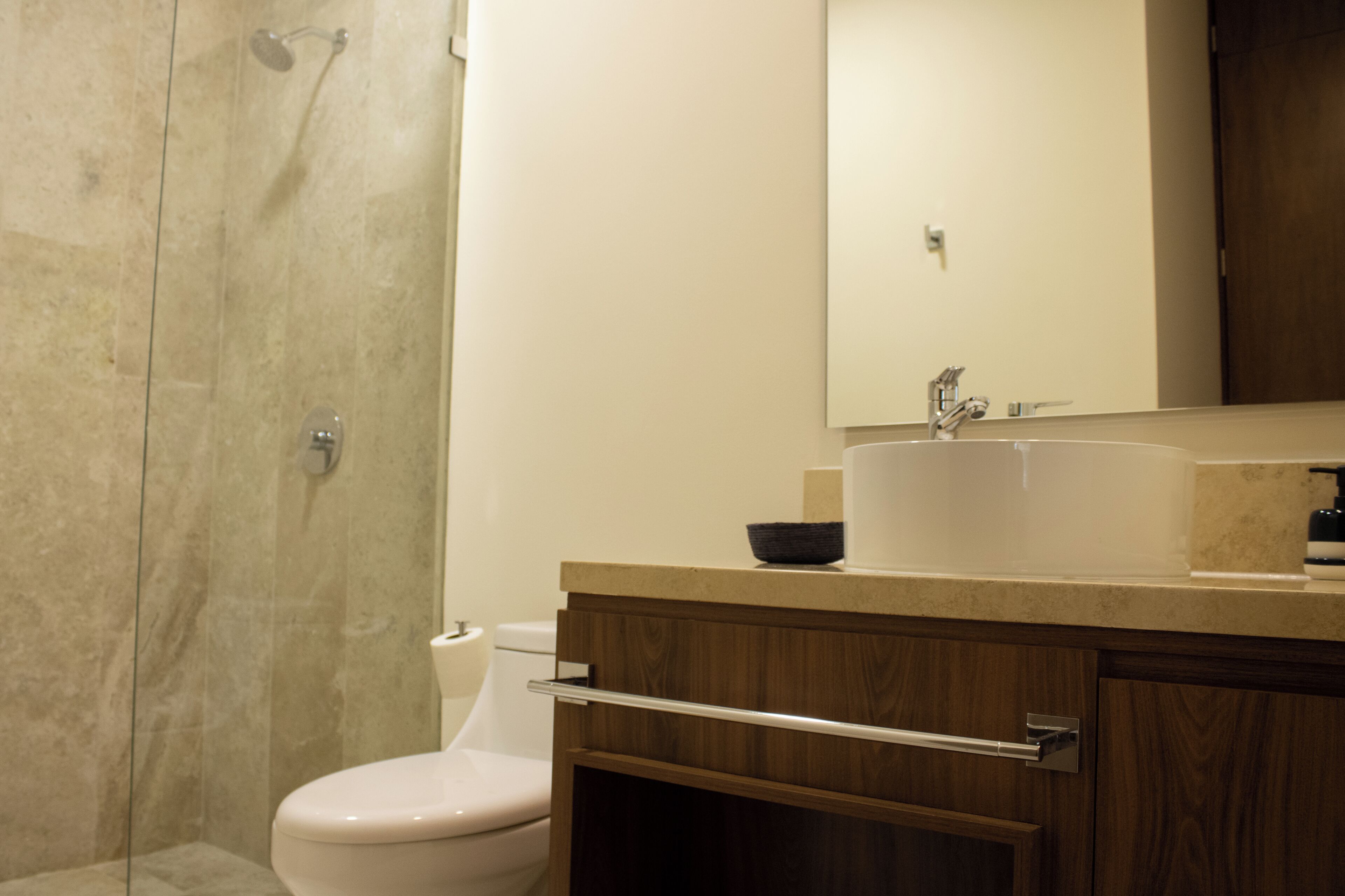 A bathroom with a shower, toilet, sink, and wooden cabinets.