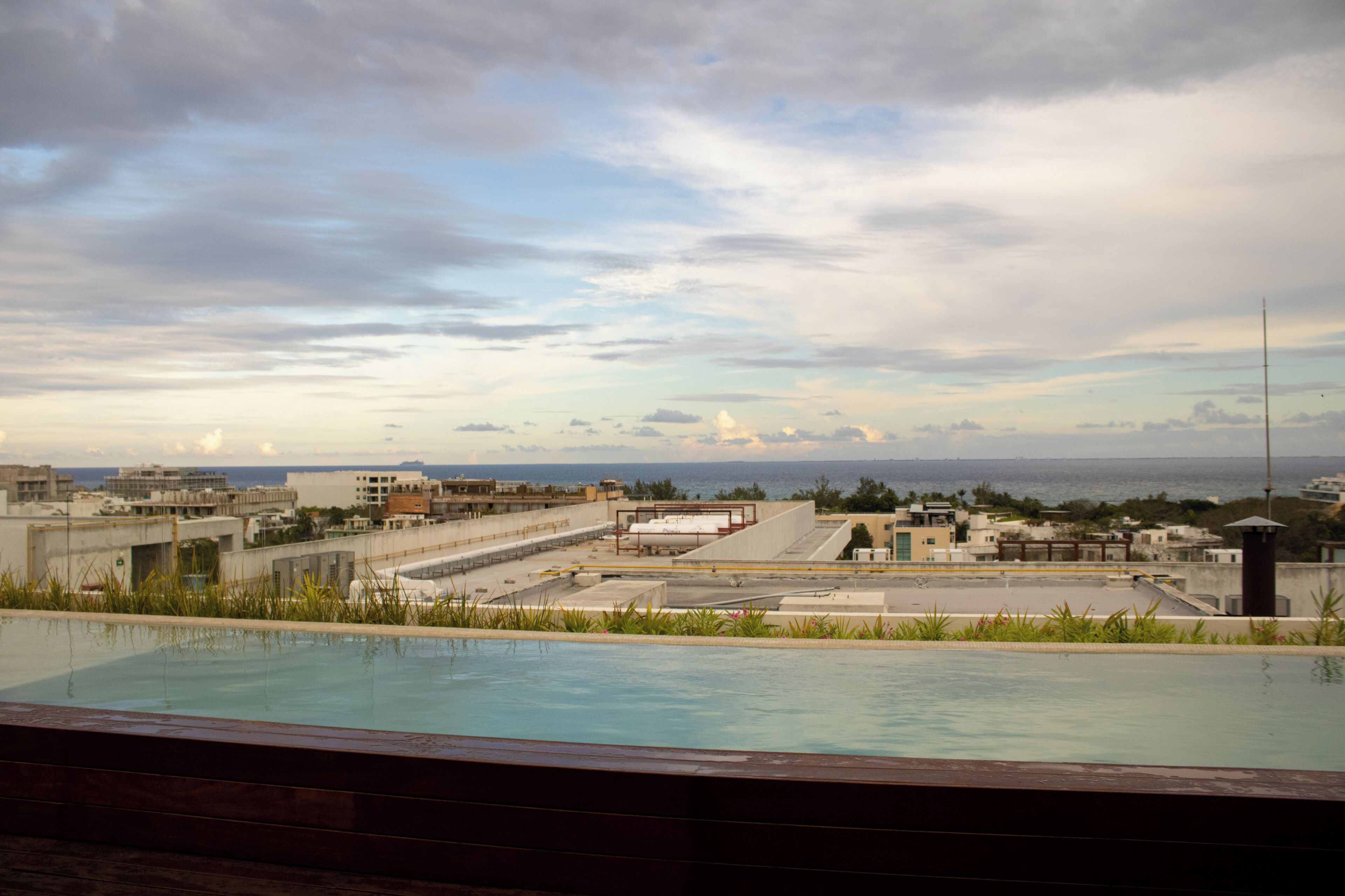 An infinity pool with a view of a cityscape and the ocean.