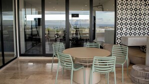 A modern dining area with a round table and four chairs, a sofa, and a patterned wall. - Paravian 107A 1BR Condo Playa del Carmen (Playa del Carmen)
