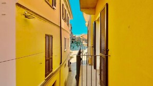 A narrow alleyway with yellow buildings, a metal gate, and a clear blue sky.