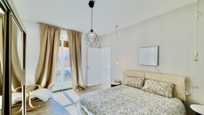 Een slaapkamer met een groot bed, een nachtkastje, een stoel, een kledingkast en een raam met gordijnen.
