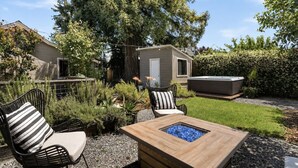 En terrasse med udendørs møbler, jacuzzi og et lille skur.