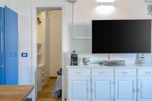 Ein Zimmer mit Fernseher an der Wand, einer Kaffeemaschine und einem Schrank mit Schubladen.