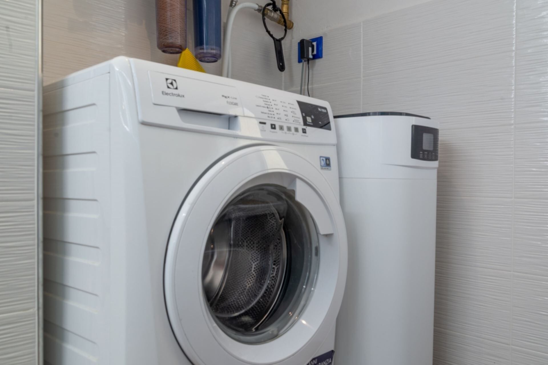 Un lave-linge à chargement frontal doté d’un panneau de commande, d’un sèche-linge et d’une prise électrique murale.