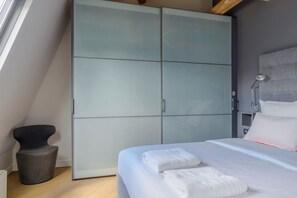 Ein Schlafzimmer mit einem Bett, einem Kleiderschrank, einem Sessel und einem Nachttisch.