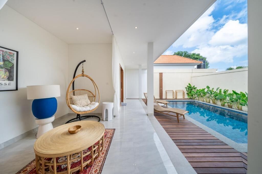 A modern interior with a pool, wicker furniture, and a clear view of the sky.