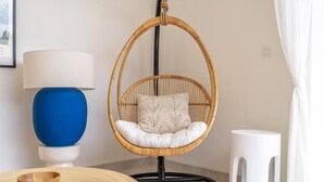 A room with a hanging chair, a blue lamp, a white stool, and a wooden bowl on a round table. - Kubung Villa Bali (Kerobokan)