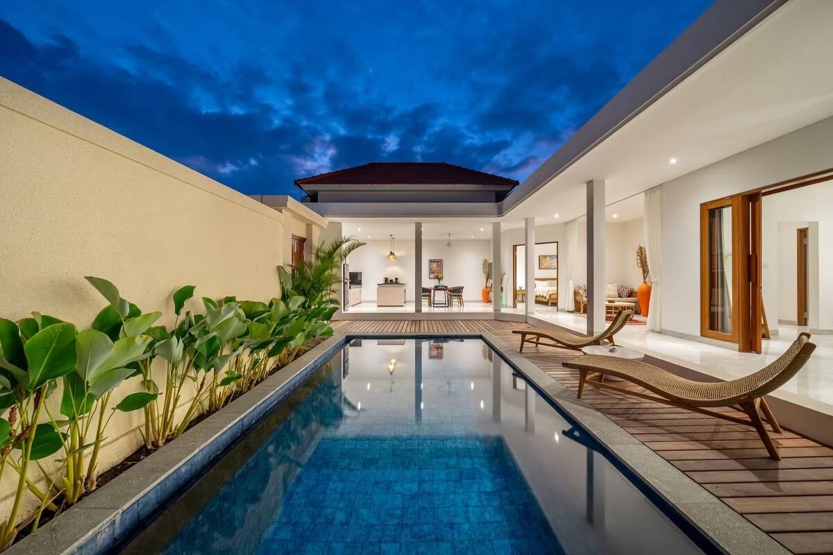 Un área de piscina moderna con vista despejada, sillones de descanso y una zona de comedor.
