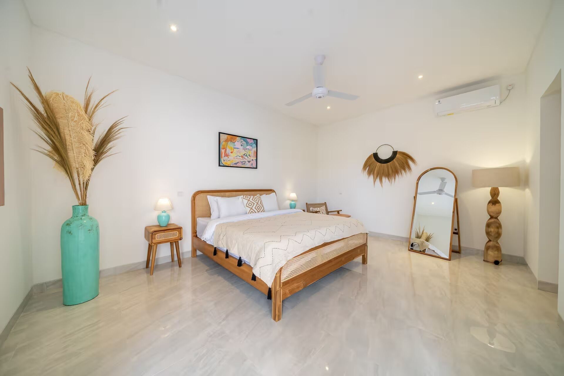 A bedroom with a bed, a standing mirror, a wall-mounted air conditioner, and a ceiling fan.