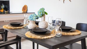 A dining table set with plates, glasses, and a vase with flowers. - Kubung Villa Bali (Kerobokan)