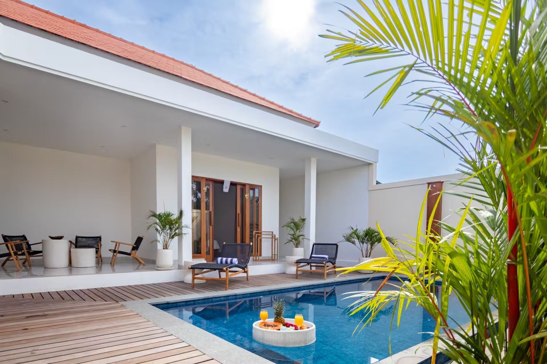 A modern outdoor pool area with lounge chairs and a wooden deck.