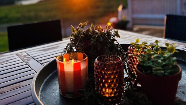 Vista del atardecer con una mesa dispuesta, velas y plantas en macetas.