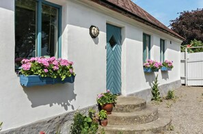 A white building with blue trim, a door with a chevron pattern, and flower boxes on the windows. - Nice holiday home in popular Österlen in Skåne! (Tomelilla)