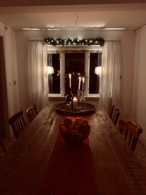 A dining room with a wooden table, chairs, a red runner, candles, and a window with curtains. - Nice holiday home in popular Österlen in Skåne! (Tomelilla)