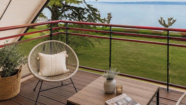 Ein Balkon mit Korbstühlen, einem kleinen Tisch und einer Zeitschrift.