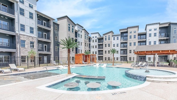 A modern apartment complex with a central swimming pool, lounge chairs, and a small hot tub. - Landing Furnished Apartments - Midlothian (Midlothian)