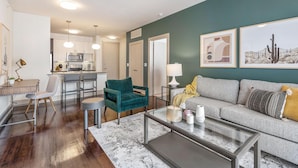 A modern living room with a sofa, coffee table, and a kitchen area in the background. - Landing Furnished Apartments - Midlothian (Midlothian)