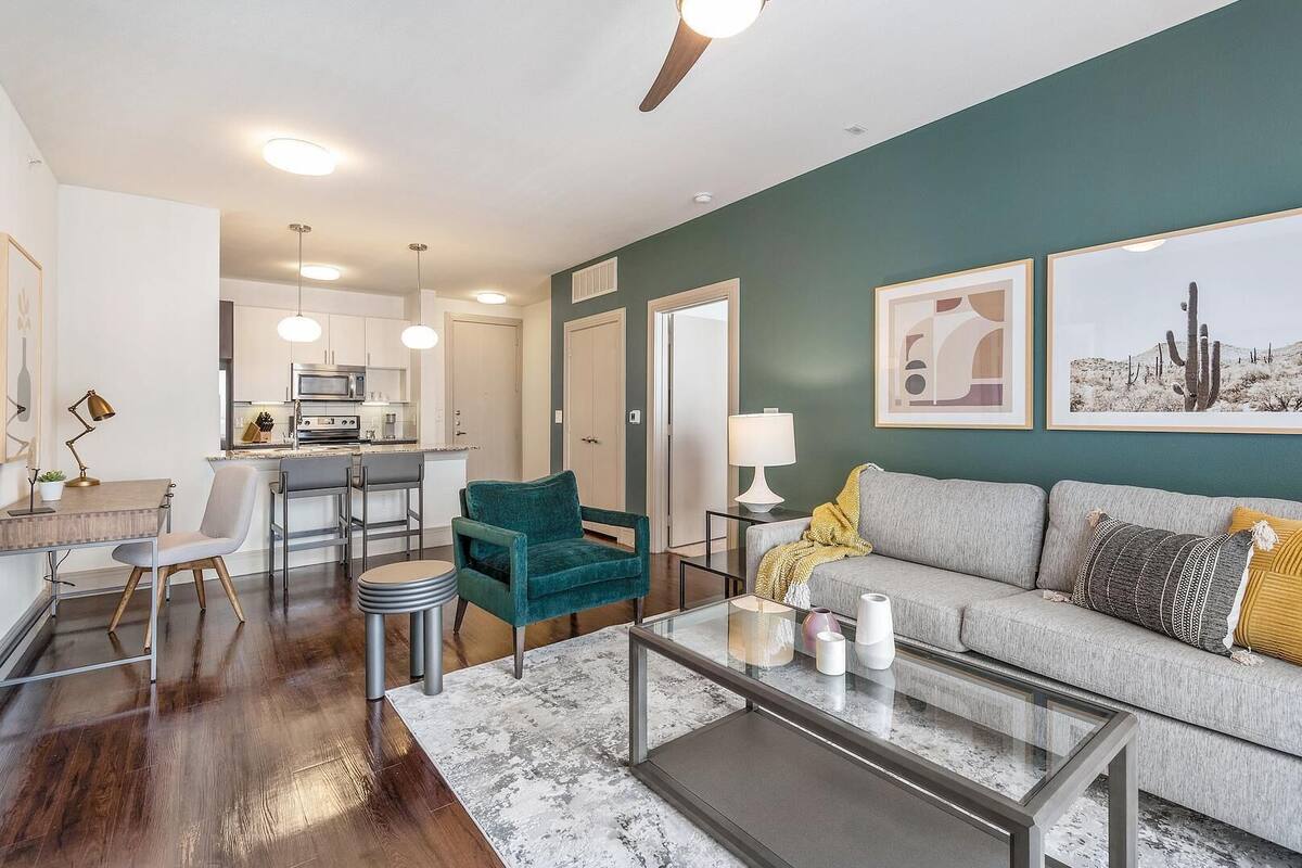 A modern living room with a sofa, coffee table, and a kitchen area in the background.