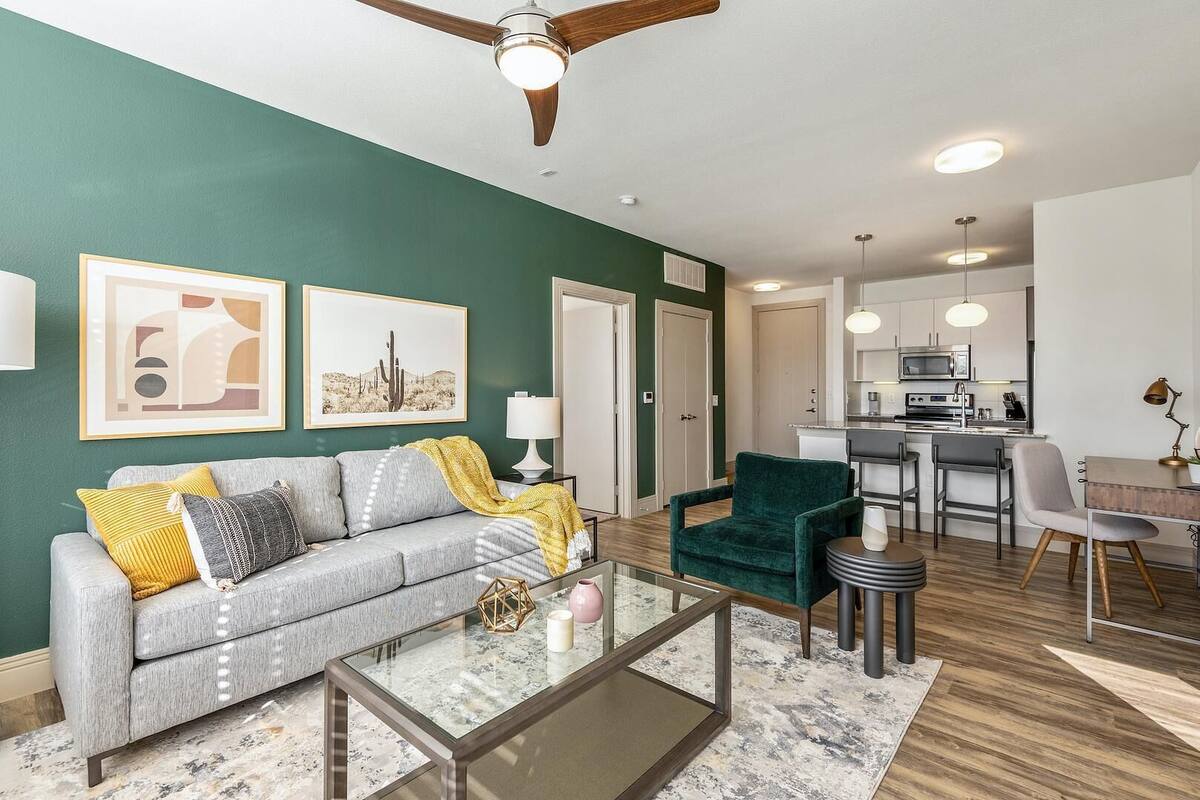 A living room with a sofa, coffee table, and a dining area with chairs and a table.