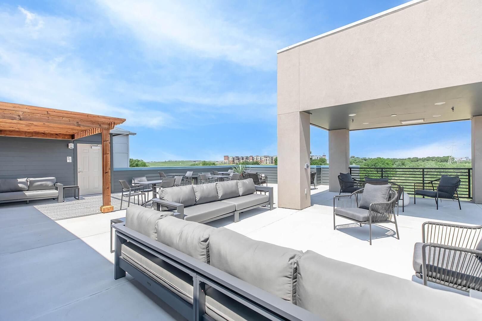 A rooftop patio with outdoor seating, a covered area, and a view of the surrounding landscape.