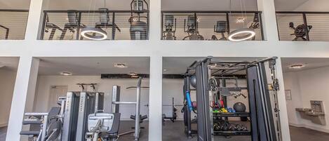 A multi-level gym with various exercise equipment, including treadmills, weight machines, and a pull-up bar area.