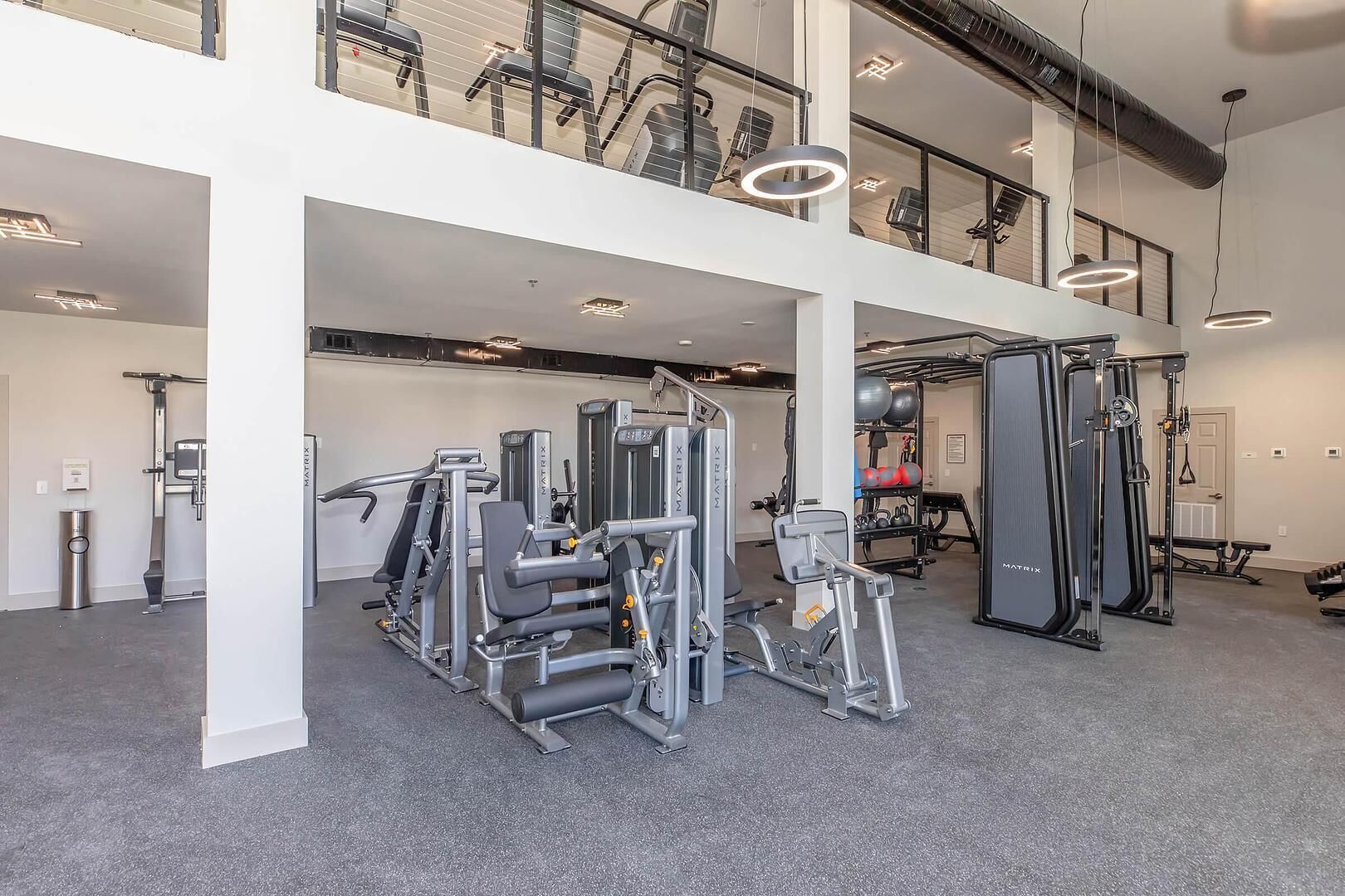 Un gimnasio de varios niveles con diversas máquinas de ejercicio, un soporte para pesas y una caminadora.