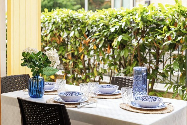 A table set with blue and white patterned tableware, a blue vase with white flowers, and a tall blue vase.