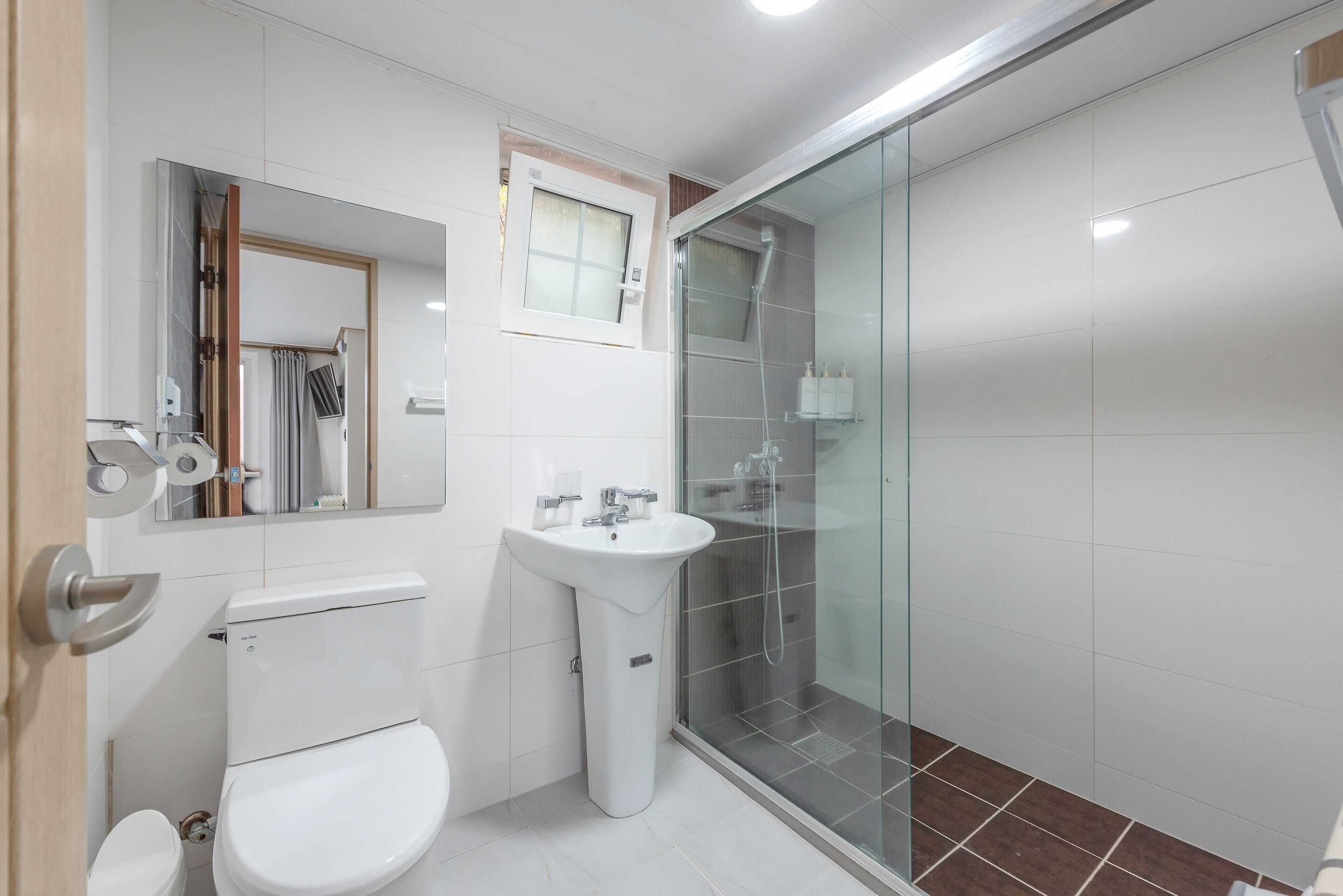 A modern bathroom with a toilet, sink, and glass-enclosed shower.