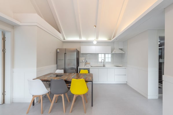 A modern kitchen with white cabinetry, a wooden dining table, and chairs.