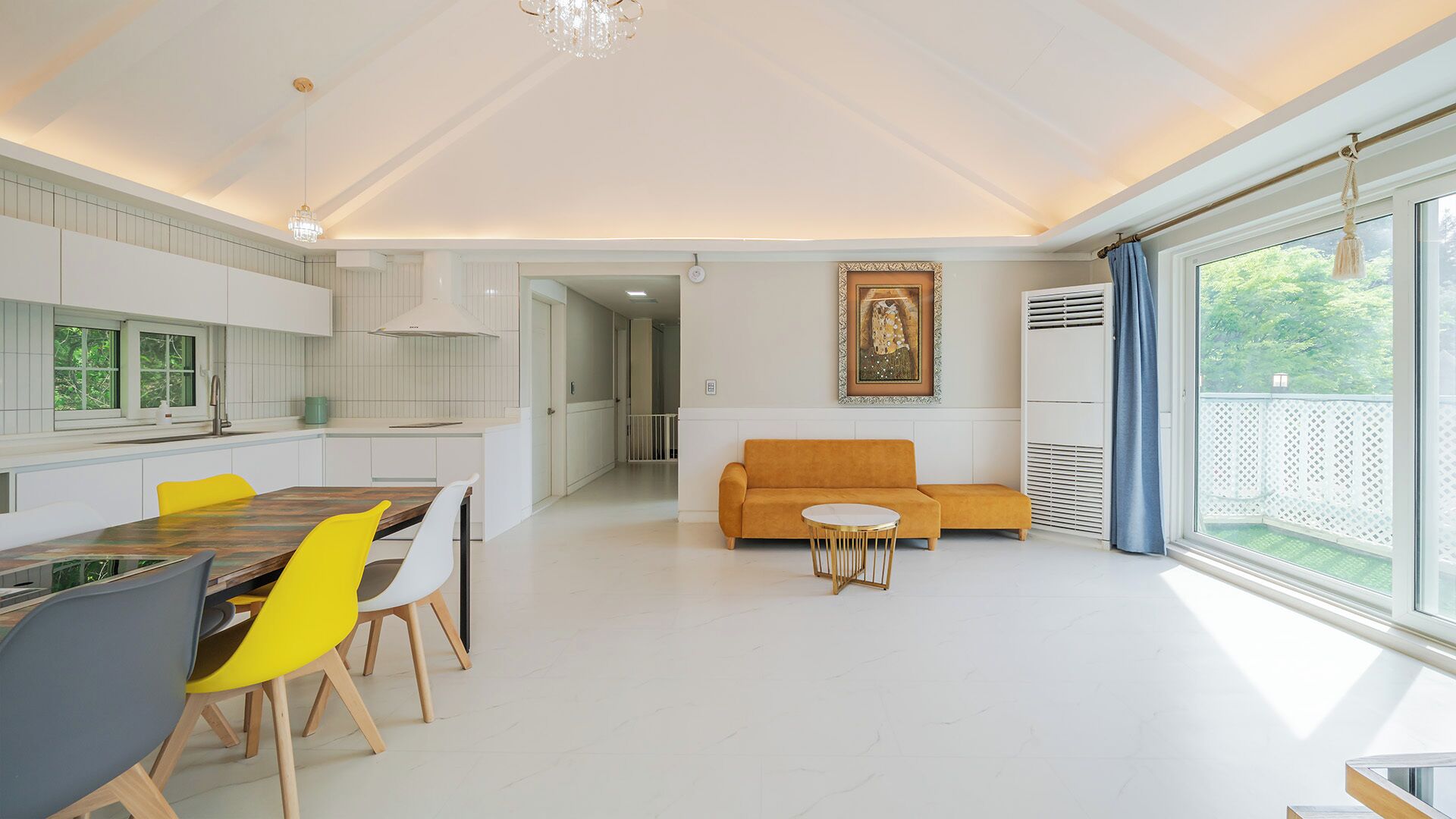 A modern living space with a dining area, a sofa, and a large window with a view.