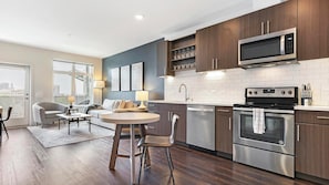 A modern kitchen with dark wood cabinets, stainless steel appliances, and a dining area with a round table and chairs.